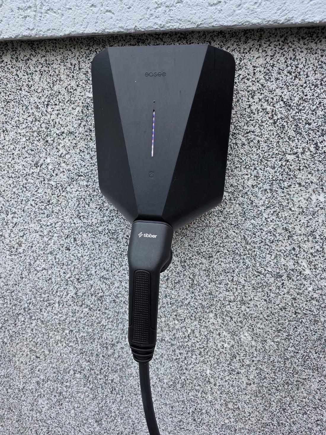Tibber eConnect Ladekabel eingehängt in eine schwarze Easee-Wallbox an einer Hauswand