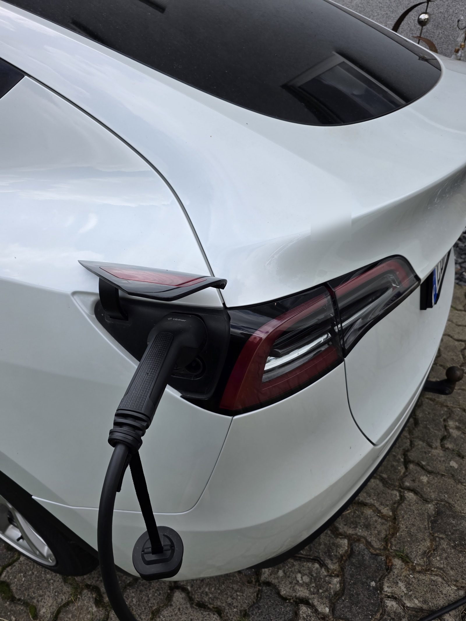 Tibber-Ladestecker im Ladeanschluss eines weißen Tesla